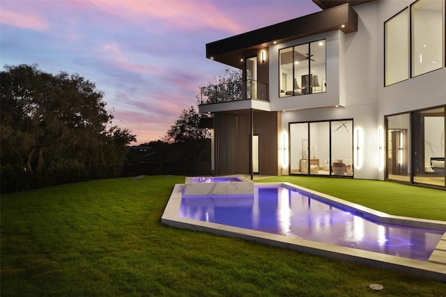 300 Stonewall Ln, Austin, TX 78746 - back of house at dusk with a balcony, a yard, and stucco siding