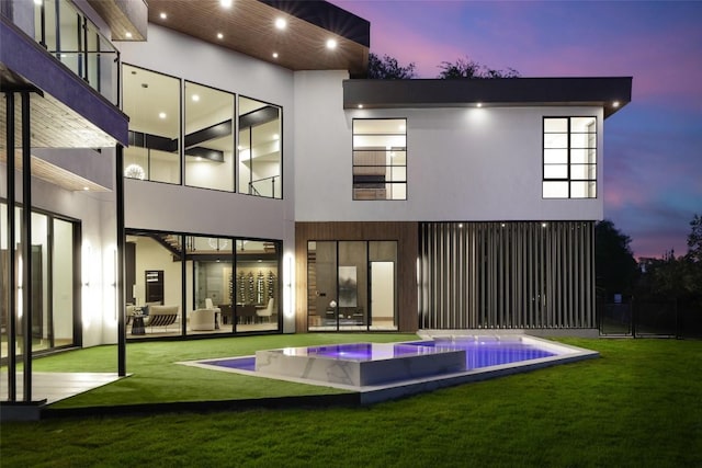 300 Stonewall Ln, Austin, TX 78746 - back of property at dusk featuring a pool with connected hot tub and stucco siding
