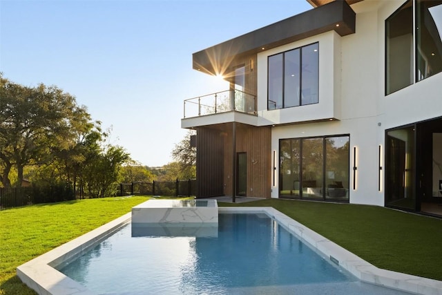 rear view of house with a balcony and a yard