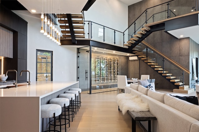 living room featuring light wood-type flooring, a towering ceiling, and sink