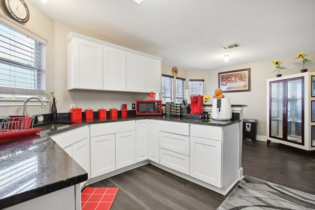 kitchen with kitchen peninsula, dark hardwood / wood-style flooring, white cabinetry, and sink