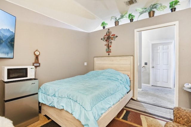 bedroom with stainless steel fridge, lofted ceiling, and carpet floors