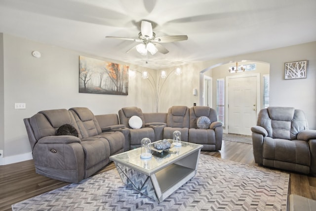 living room with ceiling fan with notable chandelier and light hardwood / wood-style floors