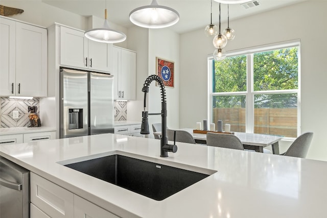 kitchen with a sink, tasteful backsplash, stainless steel refrigerator with ice dispenser, and light countertops