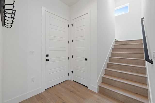 foyer with stairway, baseboards, and wood finished floors