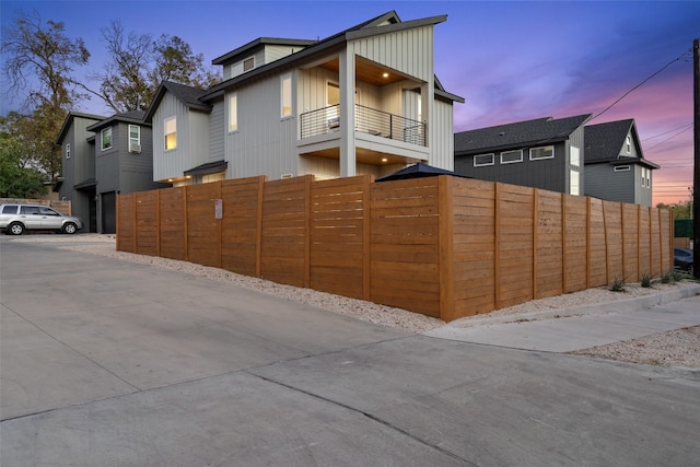 exterior space featuring a fenced front yard, board and batten siding, and a balcony