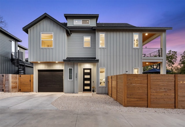 view of front of home with a shingled roof, board and batten siding, a balcony, a garage, and driveway