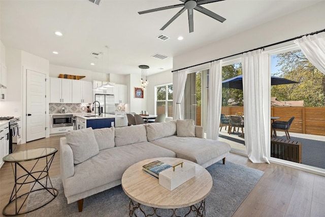 living area featuring light wood finished floors, visible vents, and recessed lighting