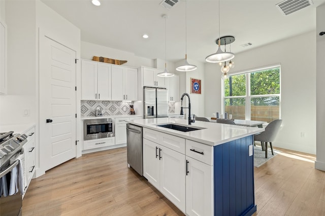 kitchen with visible vents, a sink, backsplash, stainless steel appliances, and light wood-style floors