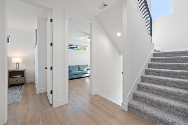 stairway featuring visible vents, baseboards, and wood finished floors