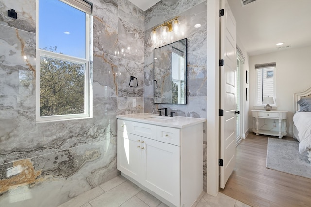 bathroom with a sink, visible vents, two vanities, and tile walls