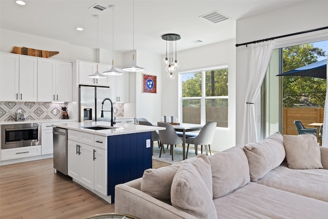 kitchen featuring visible vents, a sink, tasteful backsplash, open floor plan, and stainless steel appliances