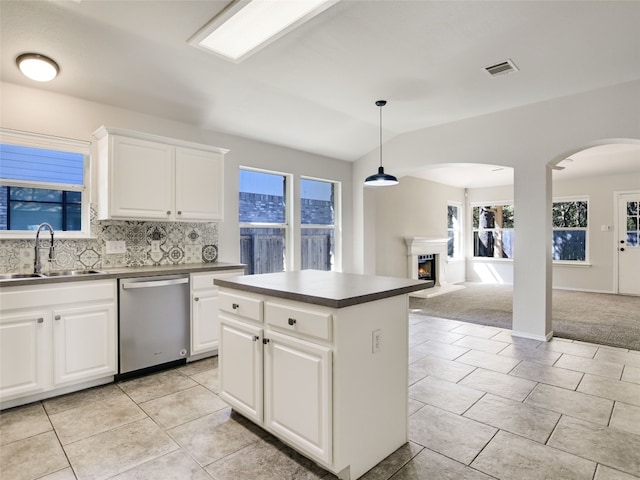 kitchen with a center island, decorative light fixtures, stainless steel dishwasher, white cabinets, and light colored carpet