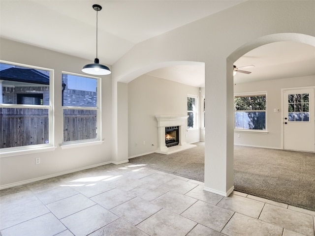 unfurnished living room featuring ceiling fan, vaulted ceiling, and light colored carpet