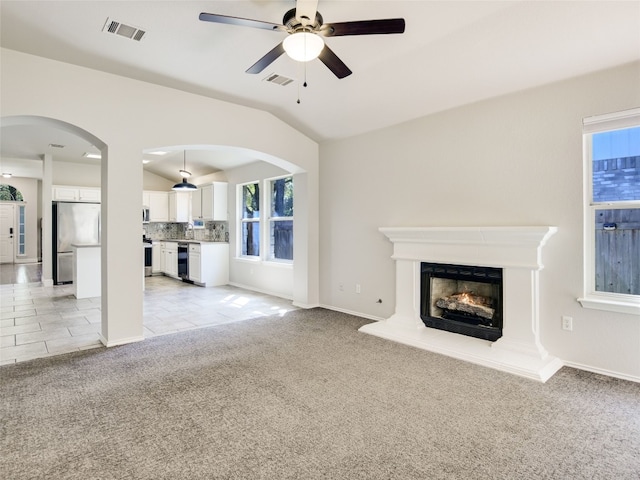 unfurnished living room with ceiling fan, lofted ceiling, and light colored carpet