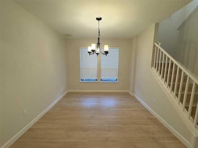 unfurnished dining area featuring a chandelier and light wood-type flooring