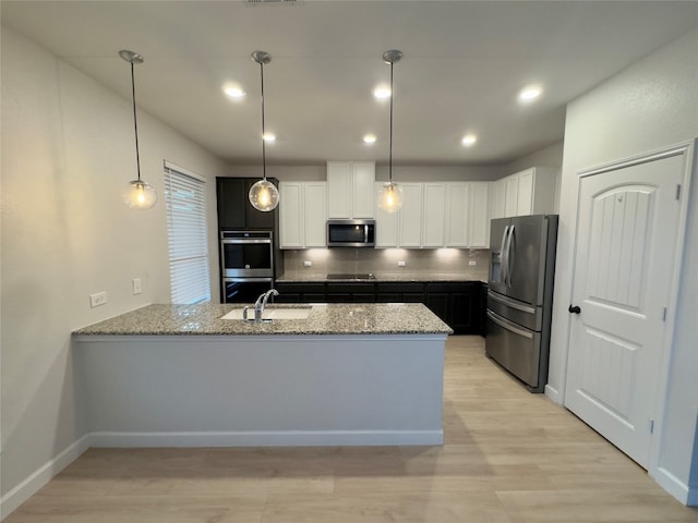 kitchen featuring appliances with stainless steel finishes, kitchen peninsula, white cabinetry, and decorative light fixtures