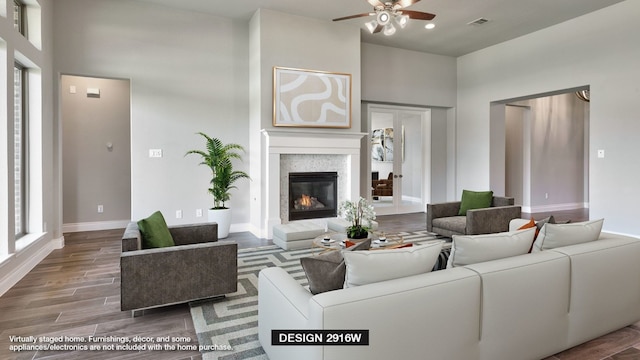 living room with a high ceiling, wood-type flooring, and ceiling fan