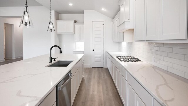 kitchen featuring white cabinets, decorative backsplash, appliances with stainless steel finishes, decorative light fixtures, and light wood-style floors