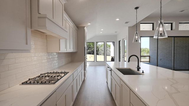 920 Teakmill Trl, San Marcos, TX 78666 - kitchen with a sink, stainless steel gas stovetop, light wood-type flooring, tasteful backsplash, and light stone countertops