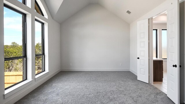 interior space with light carpet, baseboards, visible vents, and lofted ceiling