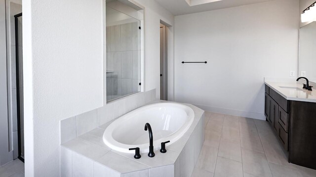 full bath featuring a garden tub, vanity, baseboards, and tile patterned floors