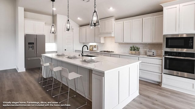920 Teakmill Trl, San Marcos, TX 78666 - kitchen featuring stainless steel appliances, a sink, decorative backsplash, an island with sink, and a breakfast bar