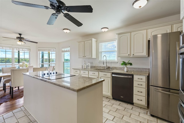 kitchen featuring dishwasher, sink, white cabinetry, light stone countertops, and stainless steel fridge