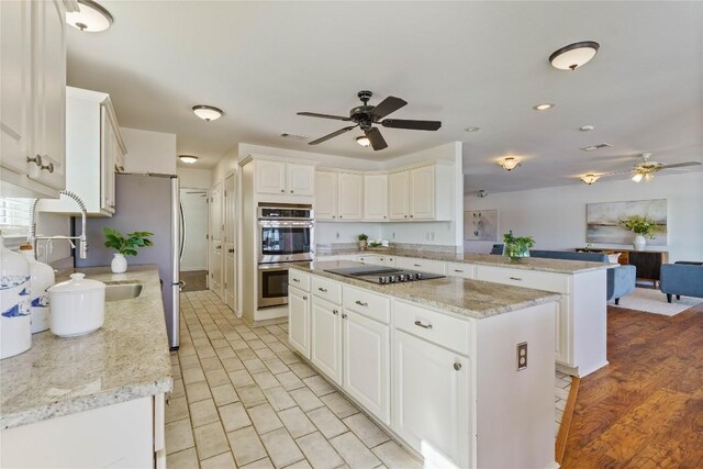 kitchen featuring kitchen peninsula, stainless steel appliances, white cabinetry, and a kitchen island