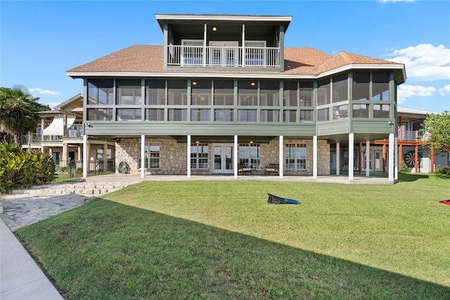 back of property with a balcony, a yard, and a sunroom