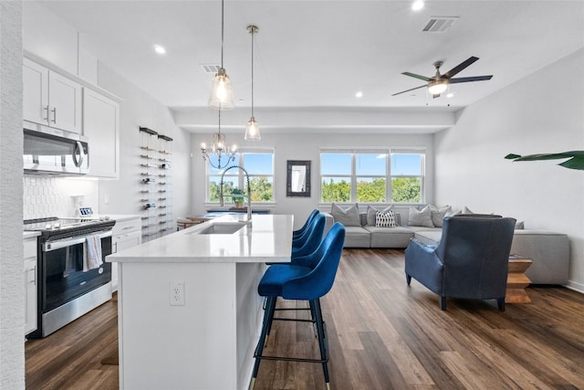 kitchen with a breakfast bar area, an island with sink, white cabinetry, dark hardwood / wood-style floors, and stainless steel appliances