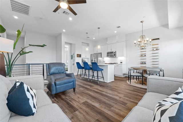 living room with dark hardwood / wood-style floors and ceiling fan with notable chandelier