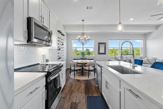 kitchen with light stone countertops, appliances with stainless steel finishes, sink, dark hardwood / wood-style flooring, and white cabinets