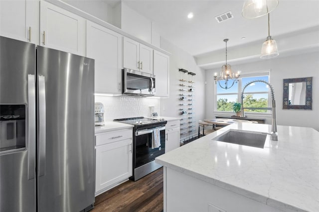 kitchen with white cabinets, dark hardwood / wood-style flooring, appliances with stainless steel finishes, light stone countertops, and sink