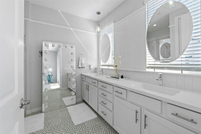 bathroom featuring vanity, a healthy amount of sunlight, decorative backsplash, and tile patterned floors