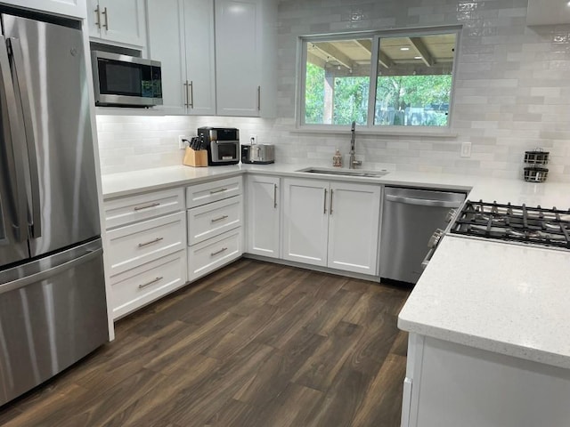 12404 Sceptre Cv, Austin, TX 78727 - kitchen featuring appliances with stainless steel finishes, tasteful backsplash, white cabinetry, and dark wood-style floors