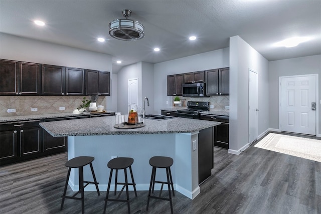 kitchen with black range with electric cooktop, sink, a center island with sink, and a breakfast bar area