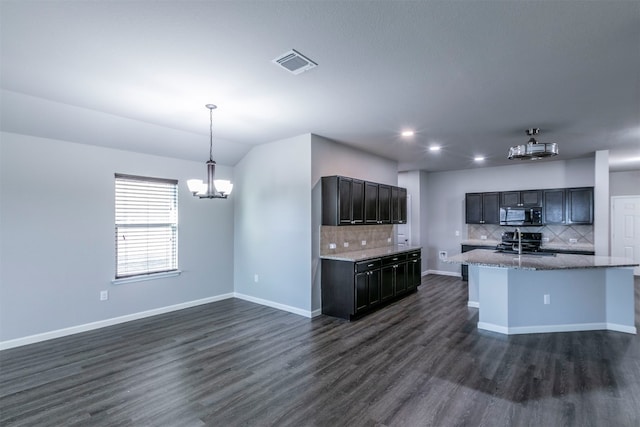 kitchen with appliances with stainless steel finishes, dark wood-type flooring, pendant lighting, and backsplash