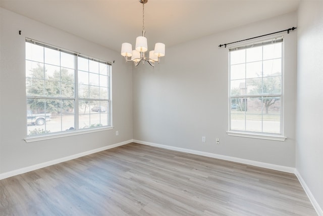 unfurnished room featuring light hardwood / wood-style floors, a chandelier, and plenty of natural light