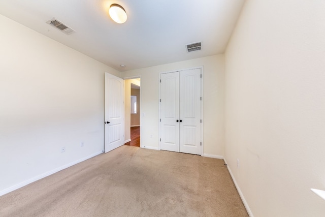 unfurnished bedroom with light colored carpet and a closet