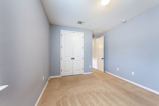 unfurnished bedroom with light colored carpet and a closet