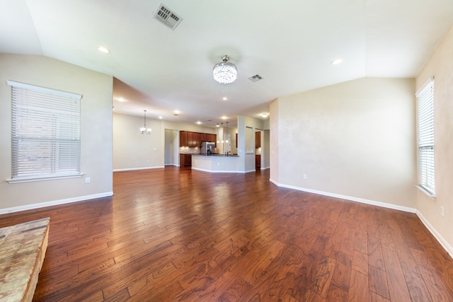 unfurnished living room with vaulted ceiling, dark hardwood / wood-style floors, and a chandelier