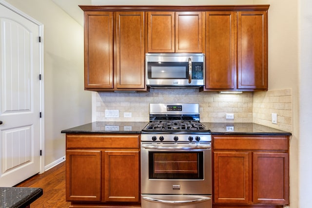 kitchen featuring backsplash, appliances with stainless steel finishes, dark hardwood / wood-style floors, and dark stone counters