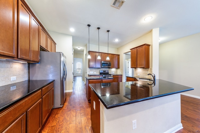 kitchen featuring stainless steel appliances, tasteful backsplash, pendant lighting, and kitchen peninsula