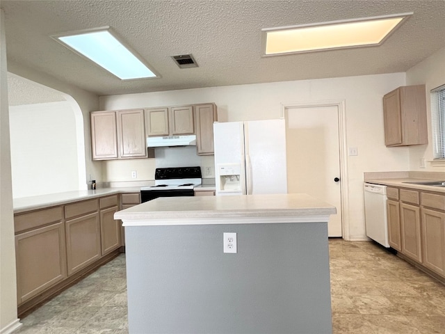 kitchen featuring light brown cabinetry, a center island, a textured ceiling, and white appliances