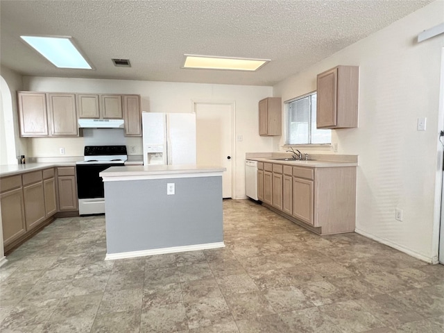 kitchen featuring white appliances, light brown cabinetry, sink, a kitchen island, and a textured ceiling