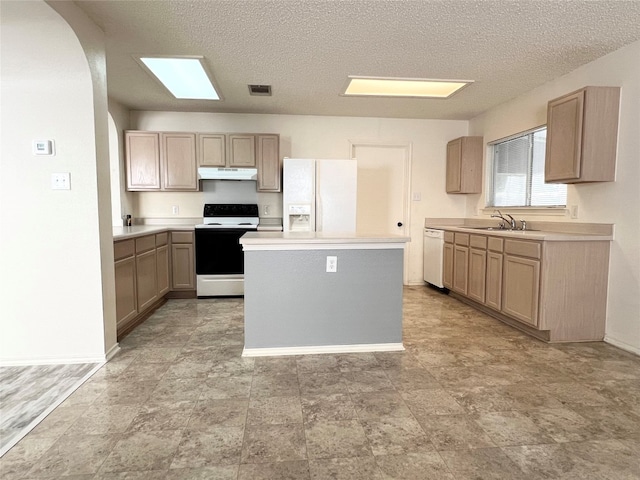 kitchen featuring a kitchen island, light brown cabinets, sink, a textured ceiling, and white appliances