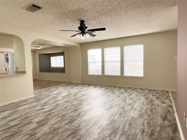 empty room with a textured ceiling, hardwood / wood-style flooring, and ceiling fan