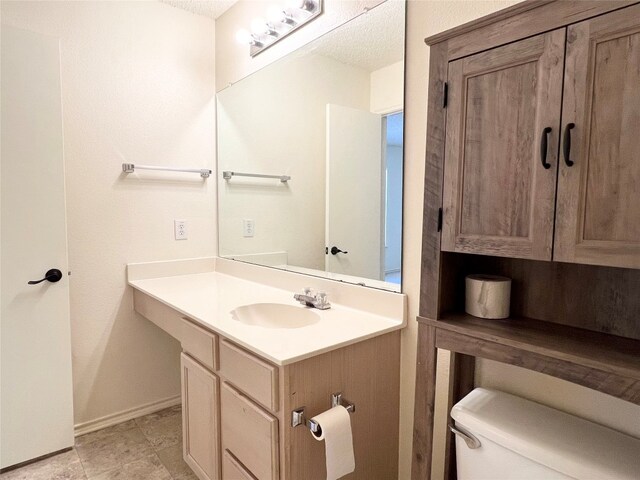 bathroom featuring toilet, a textured ceiling, and vanity