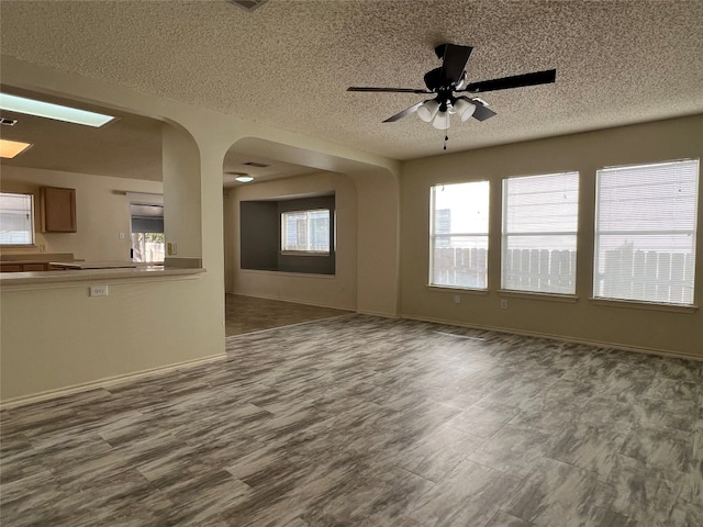 unfurnished living room featuring a textured ceiling, wood-type flooring, and ceiling fan